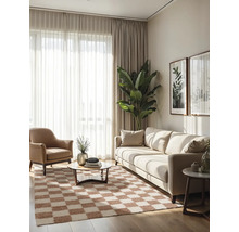 Moderne, lichte woonkamer met lichte bank, bruine fauteuil, geblokt vloerkleed, gordijnen en grote kamerplant.