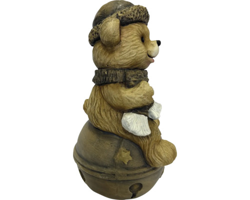 Decoratieve bruine beer met wintermuts en sjaal zittend op een bel met sterrenmotief.