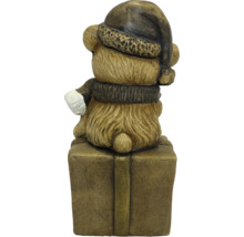 Kerstfiguur beer achteraanzicht met kerstmuts en sjaal, zittend op een cadeauverpakking.