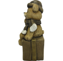Decoratiefiguur beer zittend op een geschenkdoos met wintermuts en sjaal.