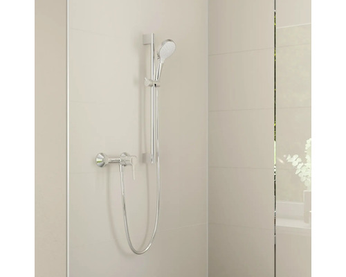 Verchroomde doucheset met handdouche, glijstang, doucheslang en eenhendel mengkraan op een licht betegelde wand.