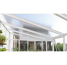 Moderne terrasoverkapping van wit aluminium met een lichtdoorlatend dak en glazen wanden tegen een witte bakstenen muur.
