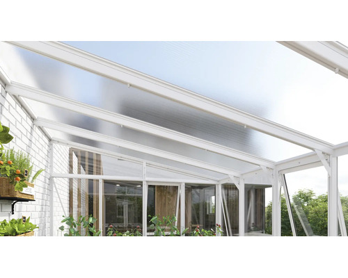 Moderne terrasoverkapping van wit aluminium met een lichtdoorlatend dak en glazen wanden tegen een witte bakstenen muur.