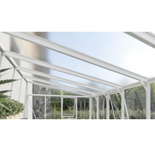 Witte terrasoverkapping van aluminium met lichtdoorlatende kanaalplaten en glazen zijwanden bij een natuurstenen muur.