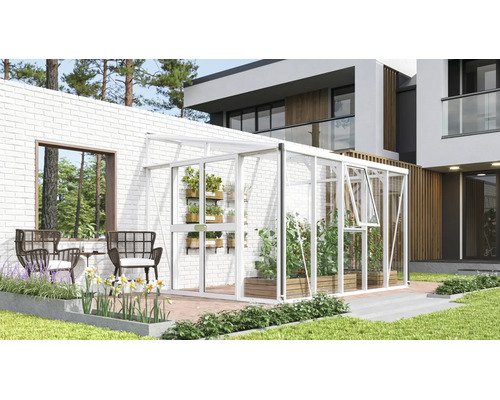 Witte aanleunkas van aluminium en glas tegen een witte bakstenen muur op een modern terras met planten en tuinmeubelen.