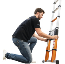 Een man knielt naast een uitschuifbare telescopische ladder van aluminium en bedient de vergrendeling van de sporten.