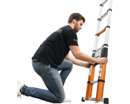 Een man knielt naast een uitschuifbare telescopische ladder van aluminium en bedient de vergrendeling van de sporten.