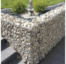 Modern tuinontwerp met een schanskorf gevuld met lichte stenen, een Boeddhabeeld op grind en groene planten naast een trap en terras.
