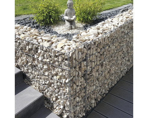 Modern tuinontwerp met een schanskorf gevuld met lichte stenen, een Boeddhabeeld op grind en groene planten naast een trap en terras.