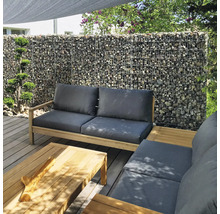 Moderne tuinlounge op houten terras met schanskorfwand op de achtergrond, houten meubels met grijze kussens en bijpassende salontafel.