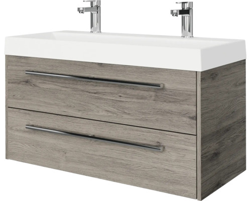 Modern badkamermeubel met dubbele wastafel, twee verchroomde kranen en een onderkast in houtlook met twee laden en metalen handgrepen.