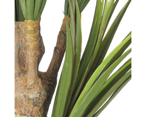 Detailopname van een kunstmatige Yucca plant met een getextureerde stam en lange, puntige bladeren.