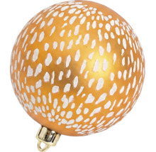 Glazen kerstbal met wit stippenpatroon op een oranje ondergrond.