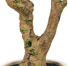 Detailopname van een kunstmatige boomstam met gestructureerde schors en moslook in een pot.