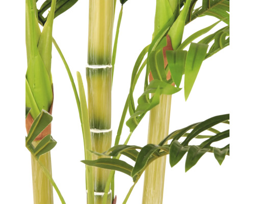 Close-up van een kunstplant met dikke stengels en groene bladeren. De stengels hebben gesegmenteerde knopen die lijken op bamboe.