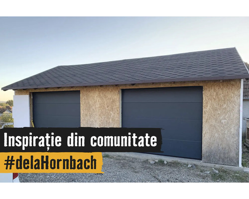 Dubbele garage in aanbouw met OSB-wandplaten, twee antracietkleurige sectionaaldeuren en een donker shinglesdak.