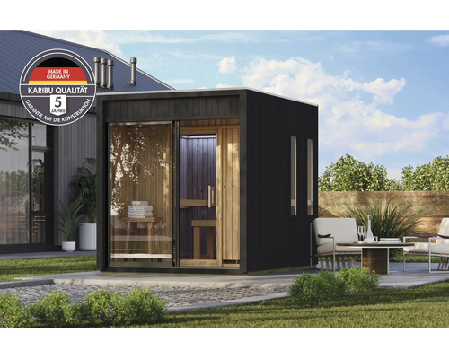 Moderne Karibu tuinsauna met glazen pui en houten interieur in een verzorgde tuin met zitgedeelte.