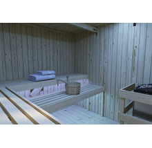 Binnenaanzicht van een moderne houten sauna met getrapte saunabanken, sauna-emmer en handdoeken en een saunakachel.