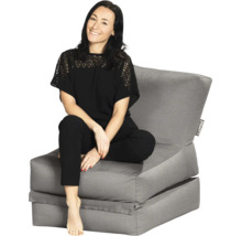 Een vrouw zit op een grijze loungestoel met rugleuning.