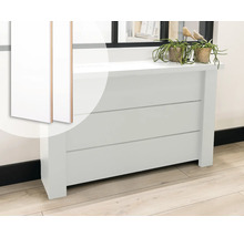 Witte radiatorombouw in modern design met rechte lamellen, gedecoreerd met planten voor een raam.