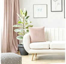 Moderne woonkamer met een witte bank, kussen met ribbelstructuur, kamerplant en gordijnen in een licht interieur.