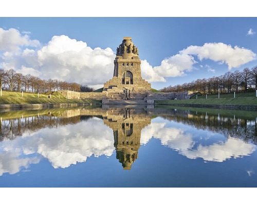 Het Monument van de Volkerenslag in Leipzig weerspiegelt in het waterbekken voor het monumentale stenen bouwwerk bij zonnig weer.
