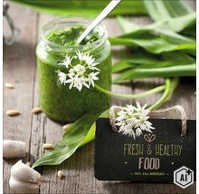 Een pot daslookpesto met verse daslookbladeren, bloemen, teentjes knoflook en pijnboompitten op een houten ondergrond met een bordje. (Image AI modified or generated)
