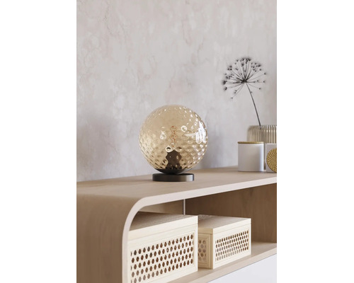 Tafellamp met een ronde glazen bol op een minimalistische voet, geplaatst op een dressoir in een modern interieur.