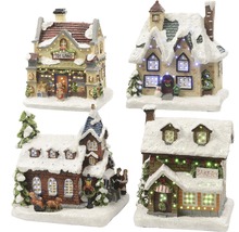 Vier kerstminiatuurhuisjes bedekt met sneeuw en verlicht.