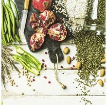 Arrangement met granaatappels, groene bonen, groene erwten, noten en kruiden op een snijplank