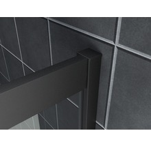 Detailopname van een douchecabine met zwart frame voor een achtergrond van tegels