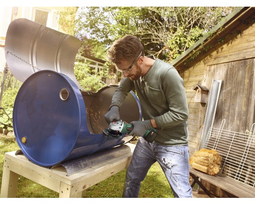 Man snijdt metalen vat met haakse slijper om tot grill