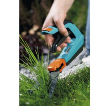 Hand die een grasschaar gebruikt om gras te knippen