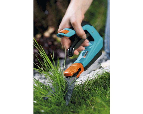 Hand die een grasschaar gebruikt om gras te knippen