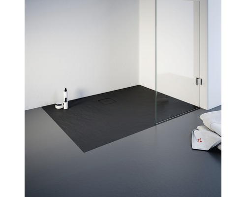 Gelijkvloerse douche met stenen douchebak, glazen douchewand en handdoeken