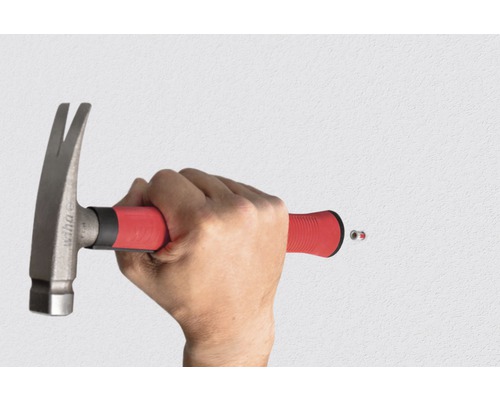 Een persoon slaat met een hamer een spijker in de muur.