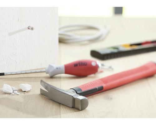 Hamer, schroevendraaier en meetinstrument liggen op de grond voor een muur.