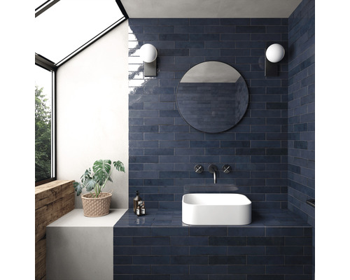 Moderne badkamer met blauwe tegels, ronde spiegel en opzetwastafel