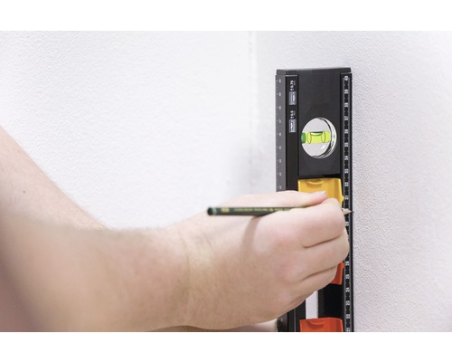 Iemand markeert een punt op de muur met een potlood, met behulp van een waterpas.