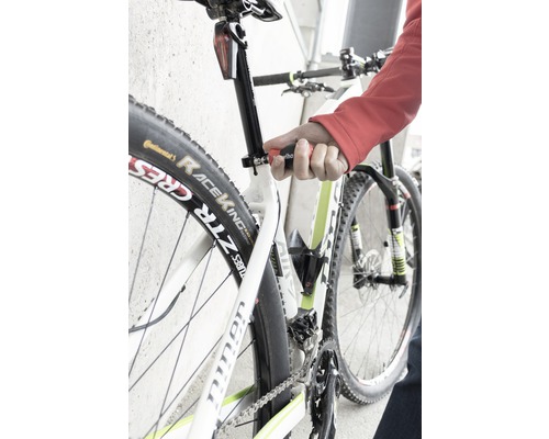 Close-up van een fiets waarvan de zadelpen wordt afgesteld met een gereedschap.