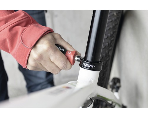 Een persoon gebruikt gereedschap op een fiets voor reparatie.