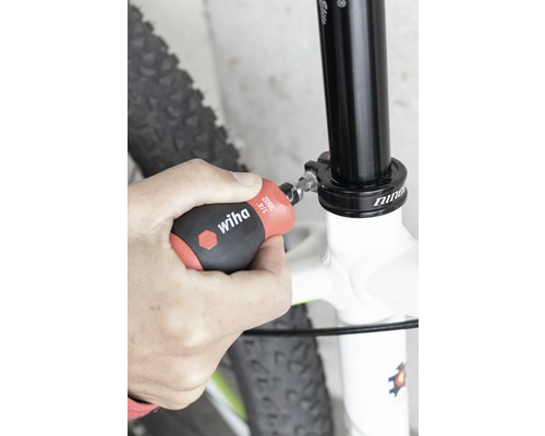 Een persoon bevestigt een fietszadelpen met een Wiha schroevendraaier.