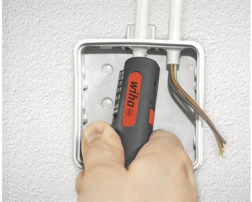 Een persoon gebruikt een Wiha draadstriptang in een verdeeldoos om kabels te bewerken.