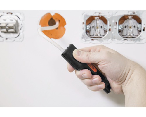 Een hand houdt een Wiha spanningstester voor een stopcontact.