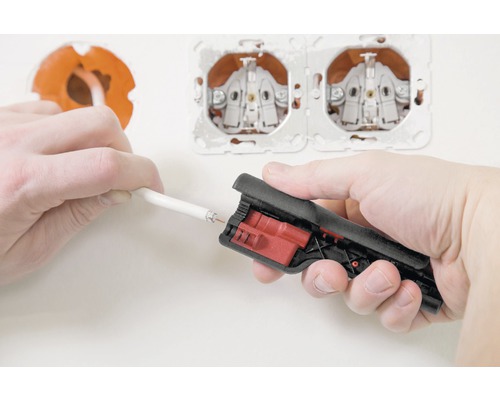 Een elektricien gebruikt een striptang om een kabel voor te bereiden voor een stopcontact.