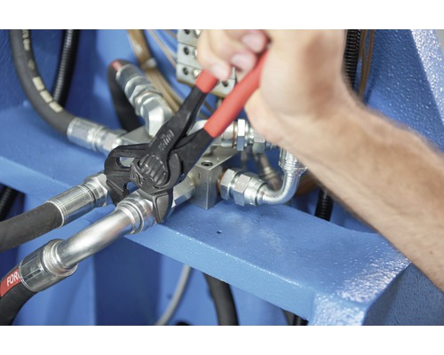 Een persoon gebruikt een waterpomptang op een hydraulische verbinding.