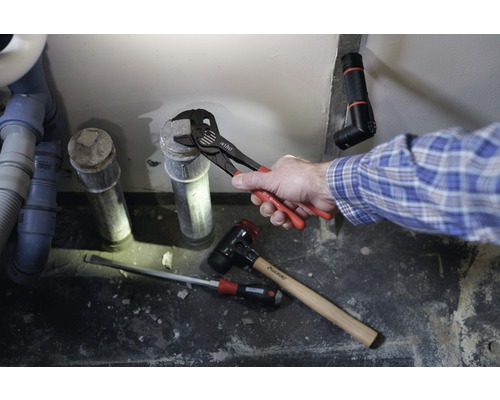 Installatie van een afvoerleiding met waterpomptang, hamer en schroevendraaier