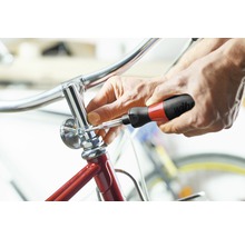 Een persoon bevestigt een onderdeel van een fiets met een schroevendraaier.