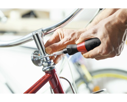 Een persoon bevestigt een onderdeel van een fiets met een schroevendraaier.
