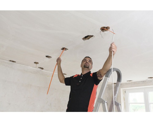 Elektricien werkt aan plafond met een kabeltrekker